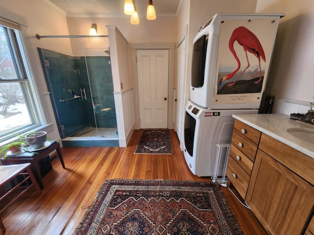 interior space featuring a notable chandelier, stacked washer and dryer, dark wood-style floors, crown molding, and laundry area