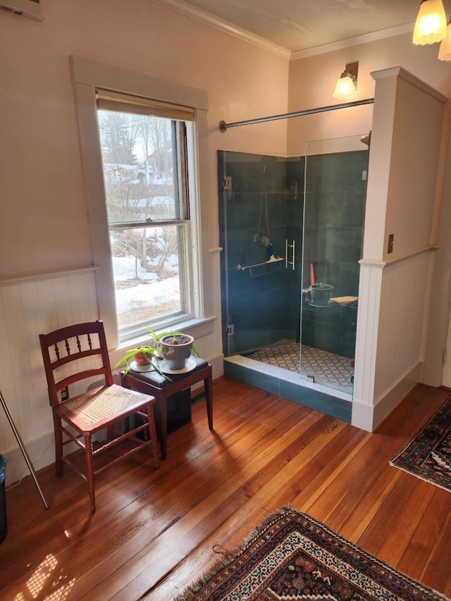 full bath featuring hardwood / wood-style flooring, a wainscoted wall, a shower stall, and ornamental molding