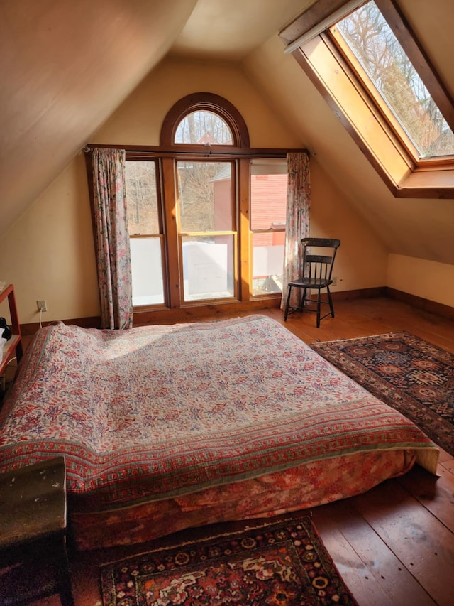 unfurnished bedroom with vaulted ceiling with skylight and hardwood / wood-style flooring