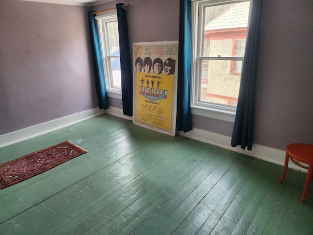 unfurnished room with baseboards and wood-type flooring