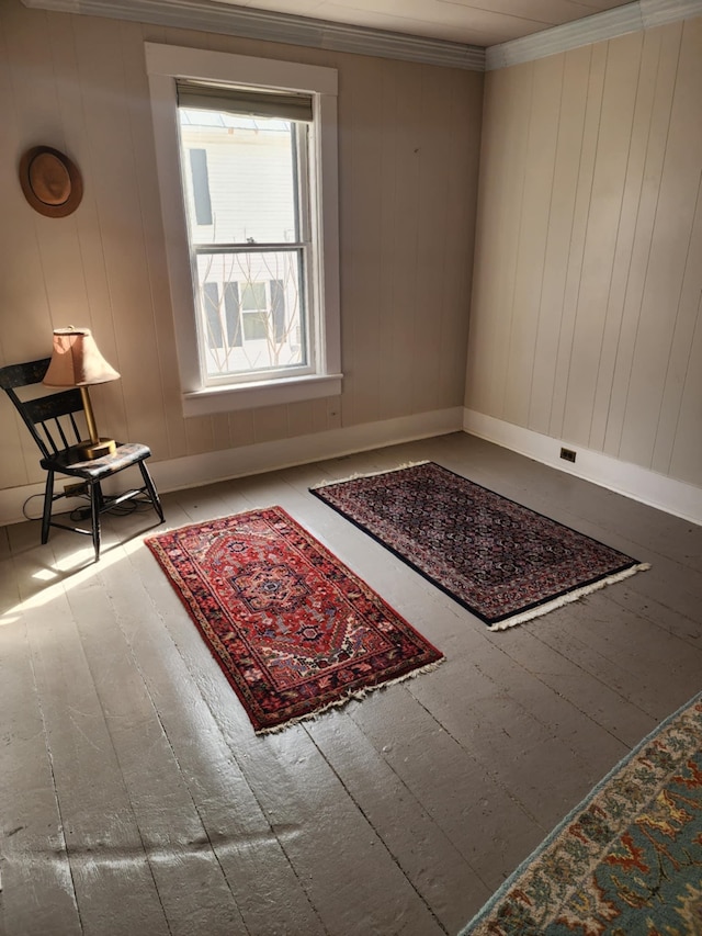 living area with baseboards, wood-type flooring, and ornamental molding