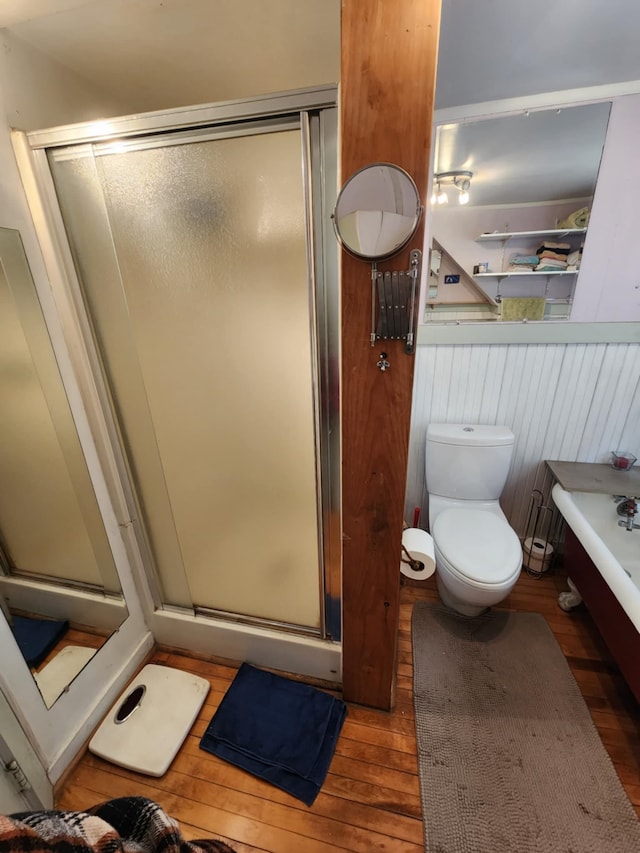 full bath featuring a bathing tub, a shower stall, toilet, and hardwood / wood-style flooring