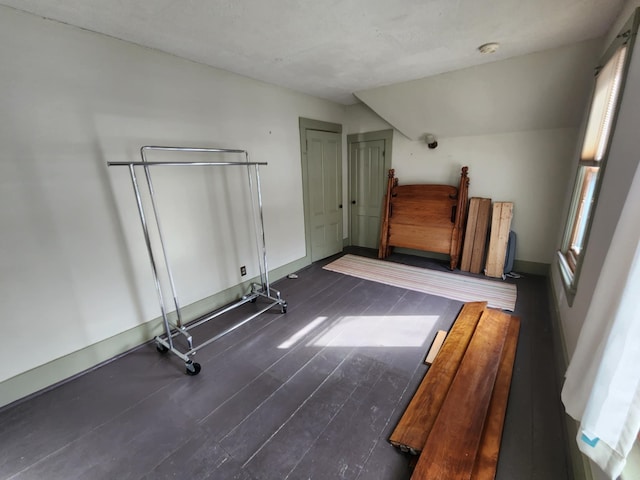 unfurnished bedroom with baseboards and dark wood-style flooring