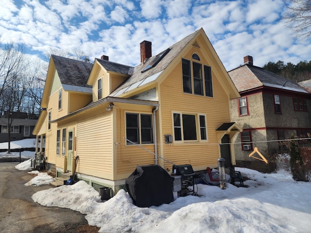 snow covered property featuring a chimney and entry steps