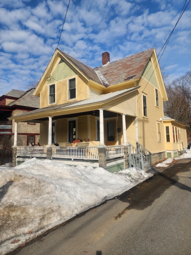 view of front of house featuring covered porch and a chimney