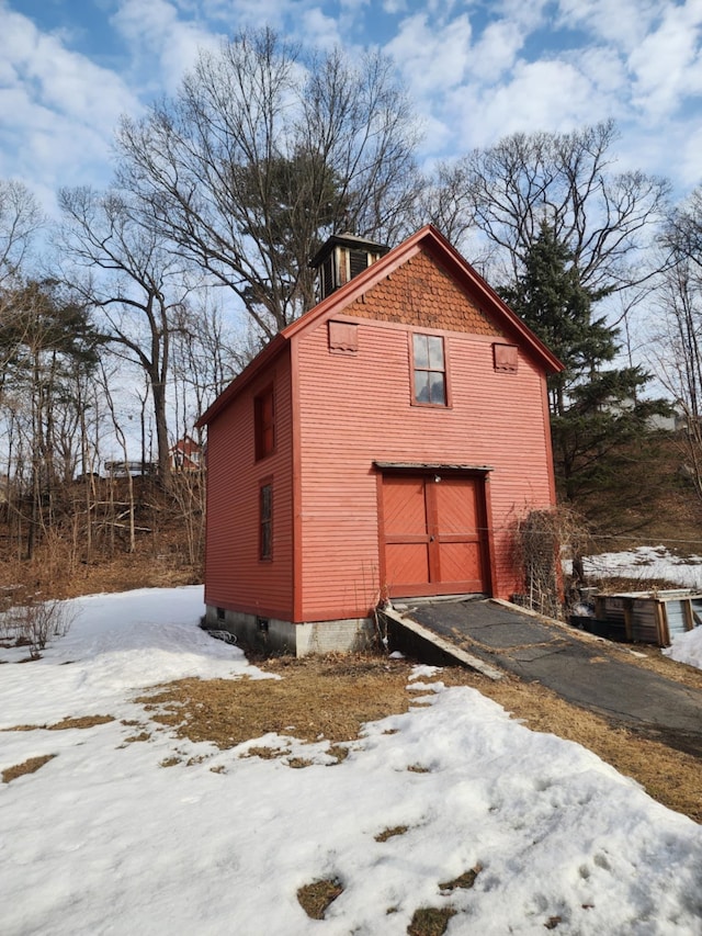 view of snowy exterior with a garage and aphalt driveway