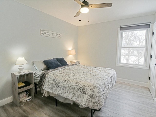 bedroom featuring ceiling fan, baseboards, and wood finished floors