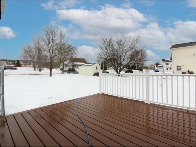 snow covered deck featuring an outbuilding and a residential view