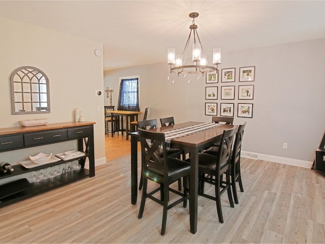 dining area with a notable chandelier, light wood-style flooring, and baseboards