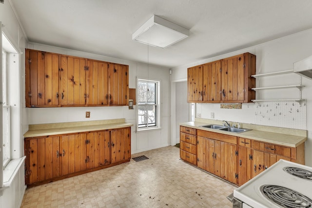 kitchen featuring a sink, light floors, brown cabinetry, electric range, and open shelves