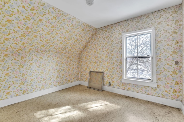 carpeted empty room featuring wallpapered walls and baseboards