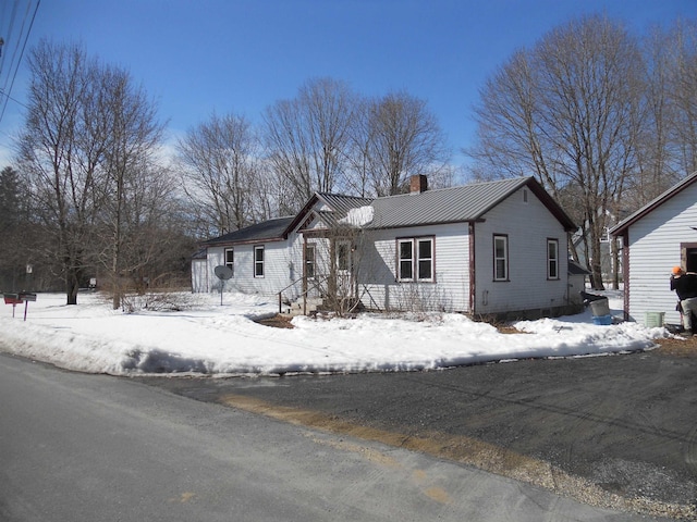 view of front of home with a standing seam roof, a chimney, and metal roof