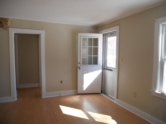 interior space with crown molding, baseboards, and wood finished floors