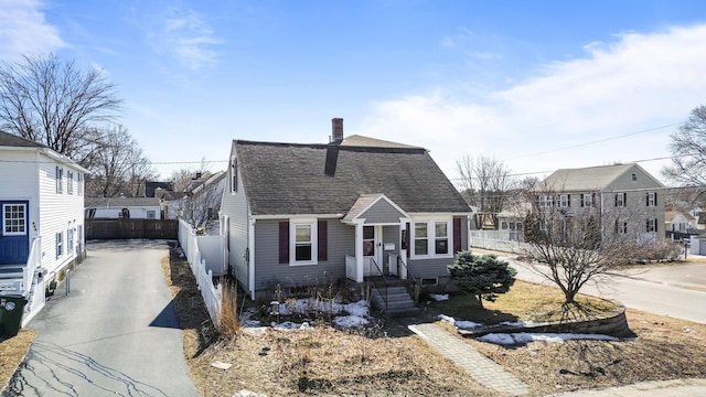 view of front of home featuring a shingled roof, fence, a residential view, a chimney, and driveway