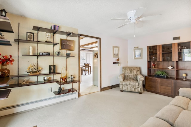 carpeted living room featuring baseboards, a textured ceiling, and a ceiling fan