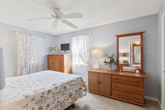 bedroom featuring light carpet, ceiling fan, a textured ceiling, and baseboards