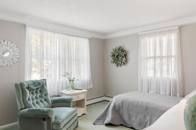 carpeted bedroom featuring a baseboard heating unit and a textured ceiling