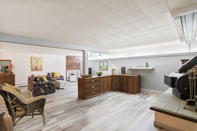 interior space featuring light wood-type flooring, baseboards, a baseboard heating unit, and a wood stove