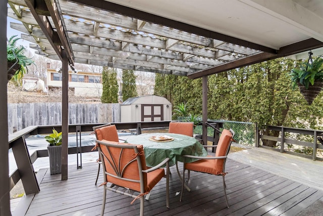 deck with outdoor dining space, a storage shed, a pergola, and an outdoor structure