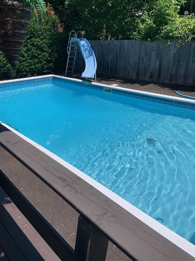 view of pool featuring a fenced in pool, a water slide, and fence