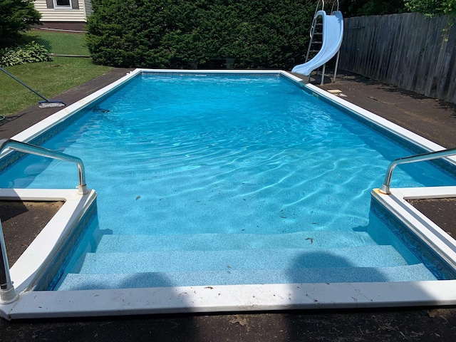 view of pool with fence, a fenced in pool, and a water slide