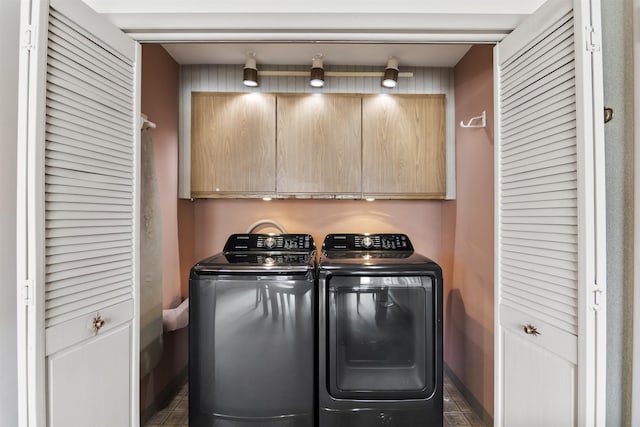 clothes washing area with washing machine and dryer and cabinet space