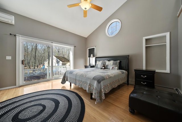 bedroom with access to exterior, multiple windows, a wall unit AC, and wood finished floors