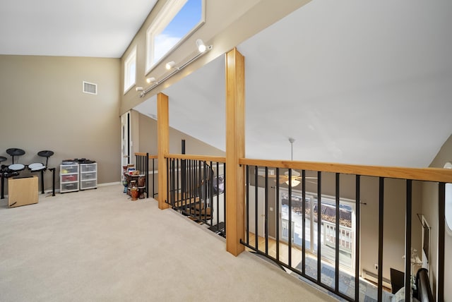 hall with a wealth of natural light, carpet flooring, visible vents, and vaulted ceiling