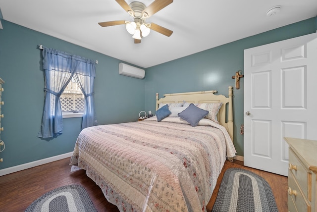 bedroom with a wall mounted air conditioner, baseboards, wood finished floors, and a ceiling fan