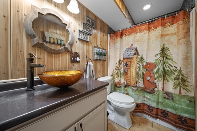 bathroom featuring vanity, a shower with shower curtain, wooden walls, and toilet