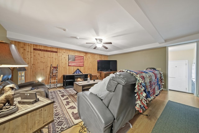 bedroom featuring ceiling fan, baseboard heating, wood finished floors, and wooden walls