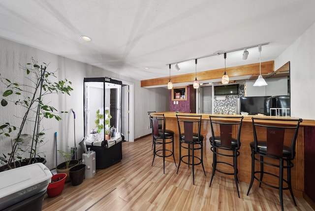 kitchen featuring a kitchen bar, wood finished floors, hanging light fixtures, and freestanding refrigerator