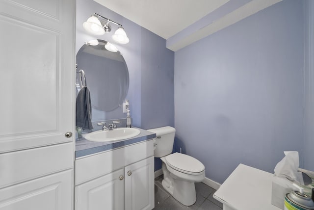 half bathroom with tile patterned floors, toilet, vanity, and baseboards