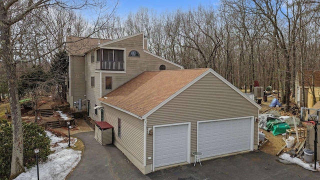 view of home's exterior featuring a garage and roof with shingles