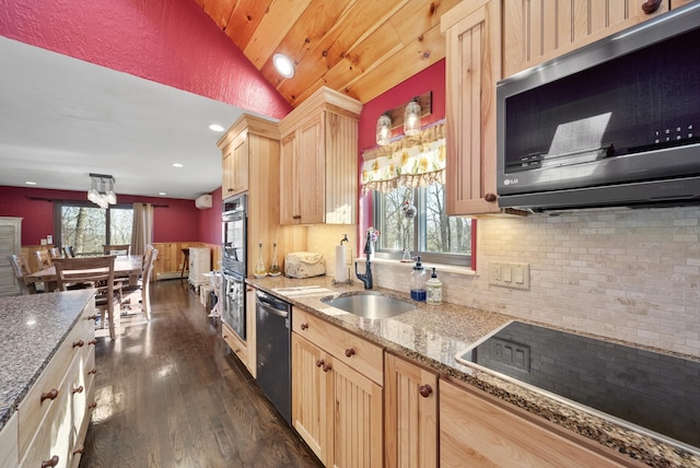 kitchen with light brown cabinets, a sink, appliances with stainless steel finishes, light stone countertops, and dark wood-style flooring