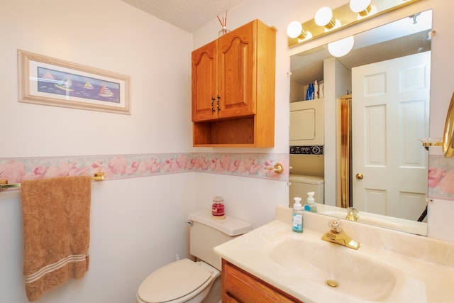 bathroom with a shower with shower door, stacked washer and dryer, toilet, a textured ceiling, and vanity