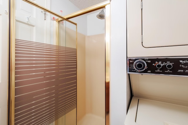 interior space with a textured ceiling, stacked washer and clothes dryer, and a stall shower