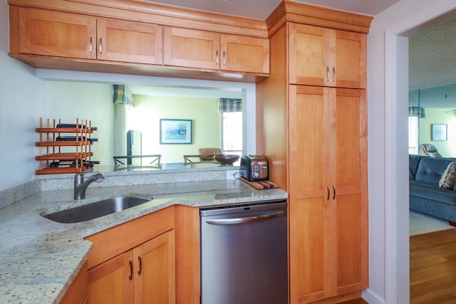 kitchen featuring a sink, light stone counters, stainless steel dishwasher, and wood finished floors