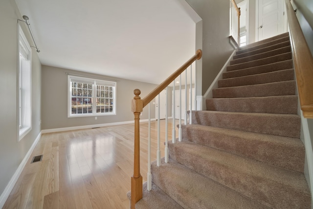 staircase featuring visible vents, baseboards, and wood finished floors