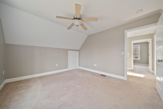 additional living space with light colored carpet, attic access, baseboards, and vaulted ceiling