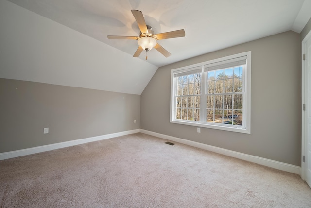 additional living space featuring visible vents, a ceiling fan, carpet flooring, baseboards, and vaulted ceiling