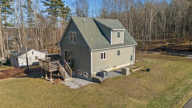 exterior space featuring a shingled roof, stairway, central AC unit, a lawn, and a deck