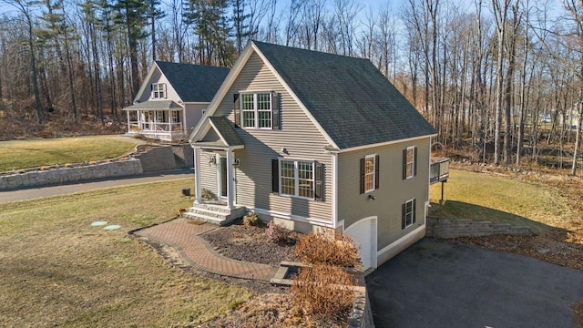 view of front facade featuring a front lawn, roof with shingles, and aphalt driveway