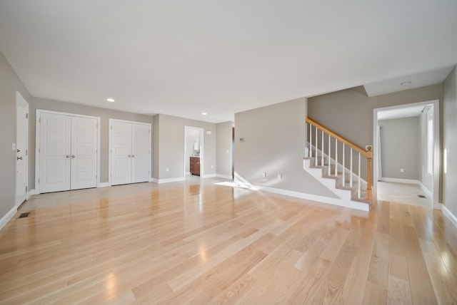 unfurnished living room featuring recessed lighting, stairway, light wood-style flooring, and baseboards