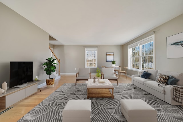 living area with light wood-style flooring, plenty of natural light, and baseboards