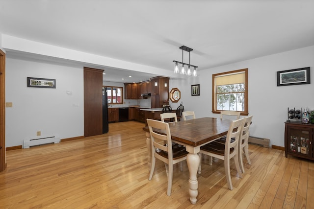 dining area featuring baseboards, light wood finished floors, and a baseboard radiator