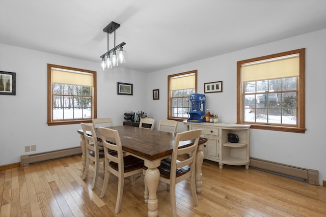 dining room featuring a baseboard heating unit, light wood-type flooring, and a wealth of natural light