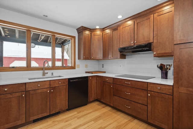 kitchen with light wood-style flooring, a sink, black appliances, light countertops, and under cabinet range hood