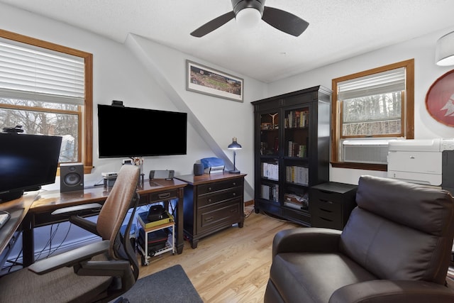 office featuring a textured ceiling, cooling unit, light wood-type flooring, and ceiling fan