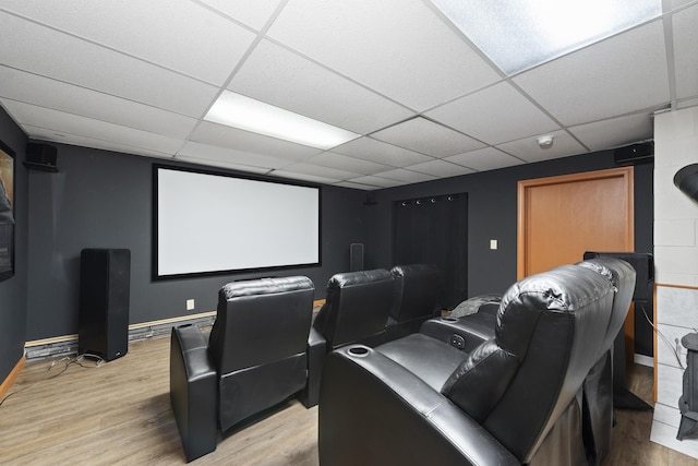 home theater room featuring baseboards, a paneled ceiling, and light wood finished floors